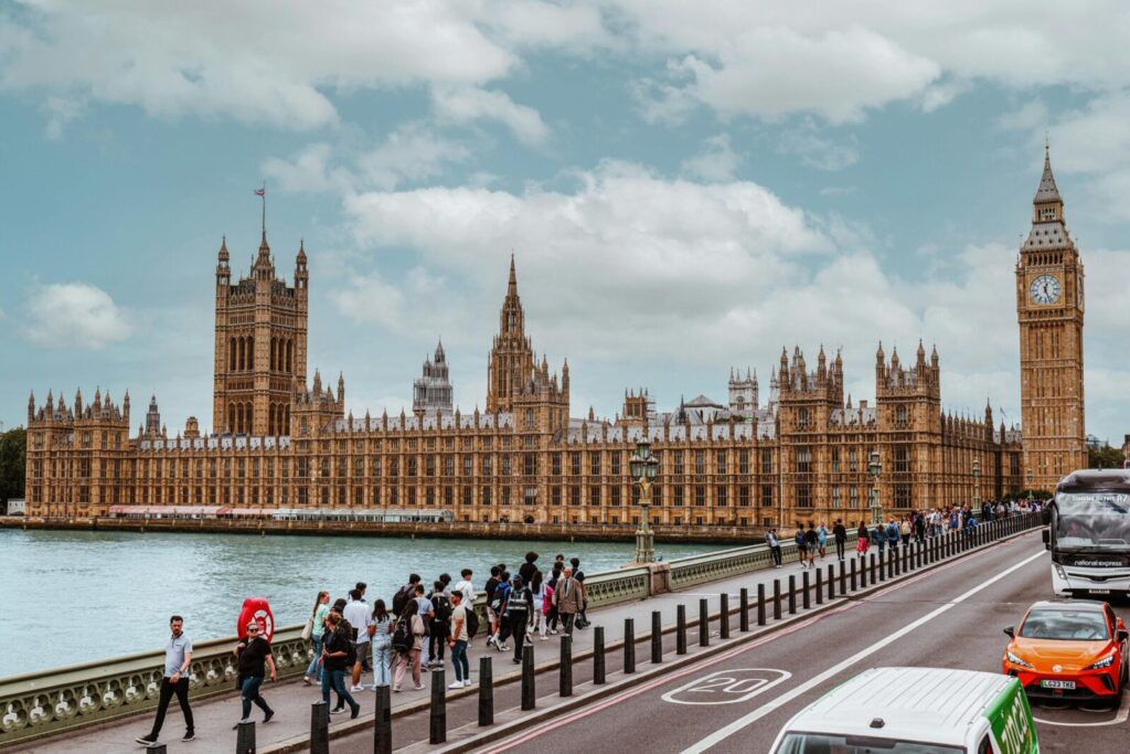 A vibrant view of Westminster Palace and Big Ben from Thames showing tourists and traffic.